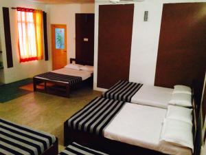 a room with two beds and a table in it at The Summer Corridor - Kataragama in Kataragama