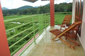 two chairs on a balcony with a view of a field at Kerala House in Thekkady