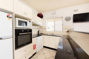 eine Küche mit weißen Schränken und schwarzen Geräten in der Unterkunft At the Beach, Debra Court Unit 5 in Forster