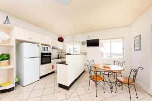 eine Küche mit weißen Geräten sowie einem Tisch und Stühlen in der Unterkunft At the Beach, Debra Court Unit 5 in Forster