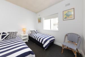 ein Schlafzimmer mit zwei Betten, einem Stuhl und einem Fenster in der Unterkunft At the Beach, Debra Court Unit 5 in Forster