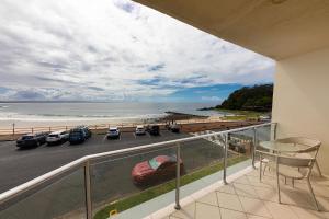einen Balkon mit Blick auf einen Parkplatz und einen Strand in der Unterkunft At the Beach, Debra Court Unit 5 in Forster