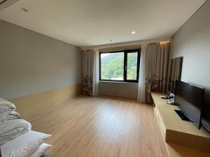 a bedroom with a television and a large window at Mudeung Park Hotel in Gwangju