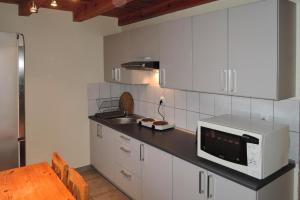 シュチェチンにあるholiday home, Szczecinの白いキャビネット、シンク、電子レンジ付きのキッチンが備わります。