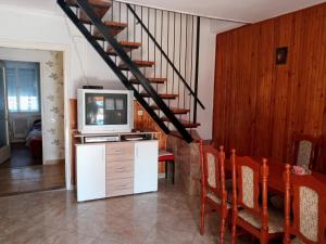 a living room with a tv and a staircase at Napsugar Nyaraló in Fonyód