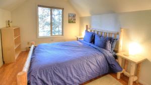 a bedroom with a bed with a blue comforter and a window at Hawks Nest Lodge in Yosemite West