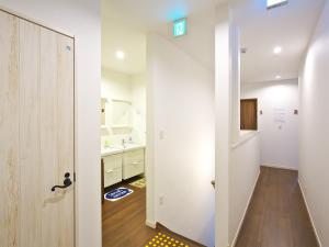 a white bathroom with a sink and a door at Shironoshita Guesthouse in Himeji