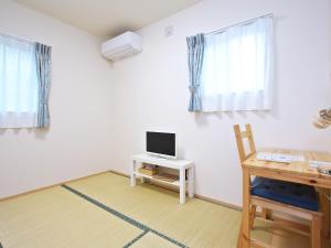 a room with a desk and a television on a table at Shironoshita Guesthouse in Himeji