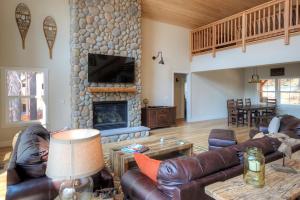 sala de estar con muebles de cuero y chimenea de piedra. en River Rock Retreat, en Yosemite West
