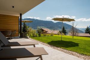 een patio met uitzicht op een gazon en een parasol bij Pataunerhof Tilia Lodge in Tirolo