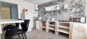 a kitchen with a white counter and black chairs at Cantinho C - Alojamento Complementar in Praia