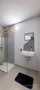 uma casa de banho com um lavatório e uma cabina de duche. em Cantinho C - Alojamento Complementar em Praia