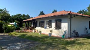 a small white house with a grass yard at Cool Landes in Sainte-Eulalie-en-Born