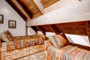 two beds in a room with wooden ceilings at Yosemite's Creekside Birdhouse in Wawona