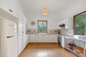 a kitchen with white cabinets and a wooden floor at Divine Cottage - Main Street Bangalow in Bangalow