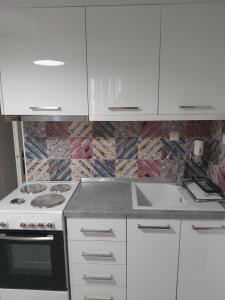 a white kitchen with a stove and a sink at Lux apartment downtown in Serres