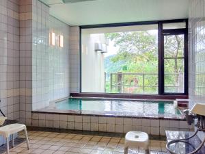 a bathroom with a swimming pool with a window at Yumeno Onsen in Kami