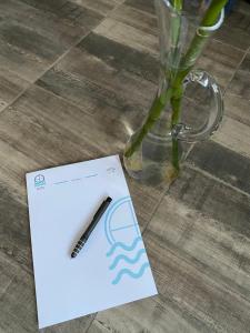 a white card with a pen on it next to a vase at Overwave Apartment in Kavála