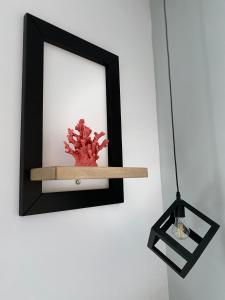 a shelf with a red plant on a white wall at Overwave Apartment in Kavála