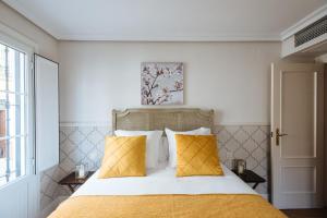 1 dormitorio con 1 cama con 2 almohadas amarillas en Magno Apartments Vidrio, en Sevilla