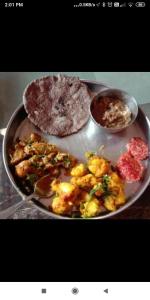 a plate of food with a pizza and other foods at Ditya's House in Mukteshwar +70 photos