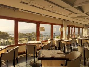 レッジョ・ディ・カラブリアにあるGrand Hotel Excelsiorのテーブルと椅子、大きな窓のあるレストラン