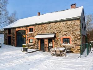 uma casa de pedra com uma mesa na neve em Gîte La Grande Francorchamps Ardennaise em Stavelot