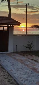 a sunset over the ocean with a building and a tree at Poovar Sea View rooms and boating Family & couple only in Pūvār