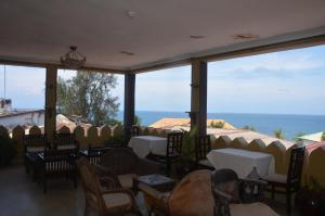 a restaurant with tables and chairs and a view of the ocean at Al Johari Hotel & Spa in Zanzibar City