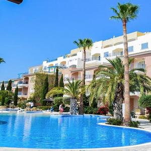 a large swimming pool with palm trees in front of a building at Aphrodite Springs in Paphos City