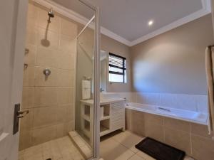 a bathroom with a shower and a sink and a tub at Relax Inn in Ballito