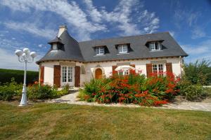 a house with a gambrel roof and some flowers at La Villa des Longchamps Location du samedi au samedi in Saint-Jouan-des-Guérets