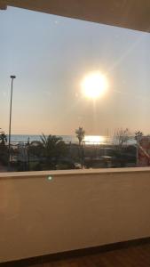 a view of the beach from a window with the sunset at casa fronte mare in Alba Adriatica