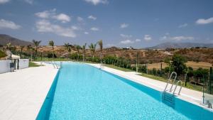 duży basen z niebieską wodą i palmami w obiekcie Stunning Apartment close to golf Mijas Spain w mieście Mijas