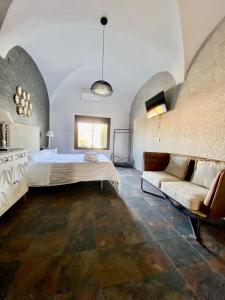 una camera da letto con un letto e un divano di Complejo Rural Rincón del Paraíso a Valencia del Mombuey