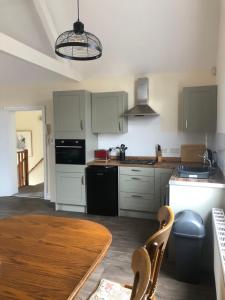 a kitchen with white cabinets and a wooden table with a dining room at Wesley Rooms Annexe in Ironbridge
