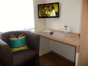 een kamer met een bureau en een tv aan de muur bij Gasthof Goldenes Lamm in Schwabsberg