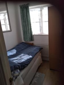 a small bedroom with a bed and two windows at 1 Double room with shared bathroom in Bracknell