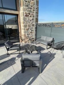 a patio with chairs and a glass table and chairs at Magnifique corps de ferme rénové avec Jacuzzi in Hillion