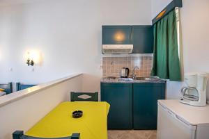 a small kitchen with green cabinets and a yellow stool at Cirillo Family Hotel-Christinas Studios in Mastihari