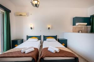 two beds in a room with green cabinets at Cirillo Family Hotel-Christinas Studios in Mastihari