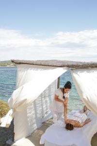 a bride and groom in a white tent on the beach at Agionissi Resort in Ammouliani