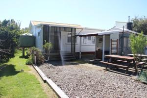 a small house with a picnic table and a bench at Cottage - Whanarua Bay Cottages in Te Kaha