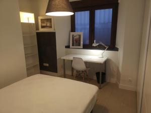een slaapkamer met een bed, een bureau en een raam bij Vive Vitoria en el Parque del Prado! U2 in Vitoria-Gasteiz
