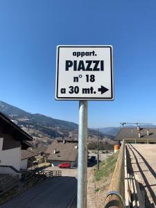 a street sign on a pole next to a road at Appartamenti Piazzi in Tesero