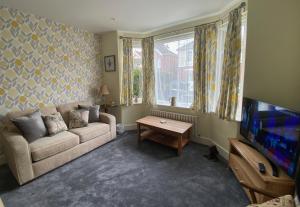 a living room with a couch and a tv at Charming 3 bed house and garden, pet friendly in Bournemouth