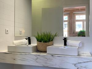 Baño blanco con 2 lavabos y espejo en Lost Inn Porto Hostel, en Oporto