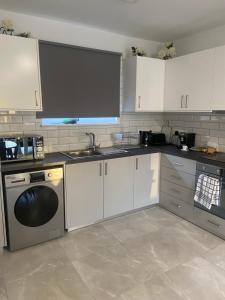 a kitchen with white cabinets and a sink and a dishwasher at Player Sea View apartment in Paphos City