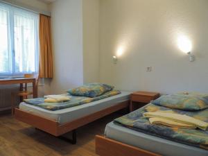 2 camas individuales en una habitación con ventana en B&B Haus Schönstatt contactless- Check-In, en Brig