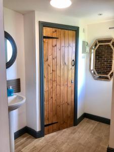 eine Holztür im Bad mit Waschbecken in der Unterkunft Valley Farm Bells in Oxford